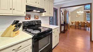 Una cocina con armarios blancos, una estufa negra y un bloque de cuchillos de madera.