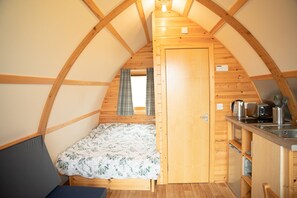 Un camping-car confortable, composé d’une seule pièce, avec un lit, une kitchenette et une fenêtre.
