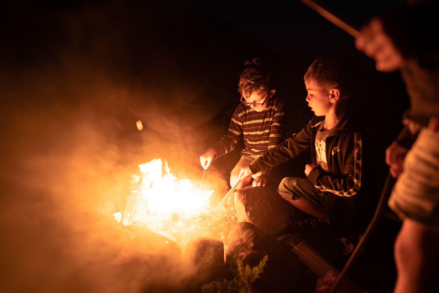 Zwei Personen sitzen nachts am Lagerfeuer.