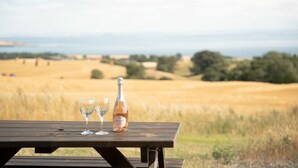 A picnic table with two empty wine glasses and a bottle of Prosecco wine. - Rural Cosy Cabin With Beautiful Views Over Fife (Leven)