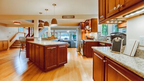 A spacious kitchen with wooden cabinets, granite countertops, and pendant lighting. - Lake Escape: The Definition of Lakefront Luxury (Canandaigua)