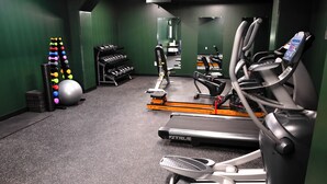 Ett gym med löpband, träningsbollar och hantlar.