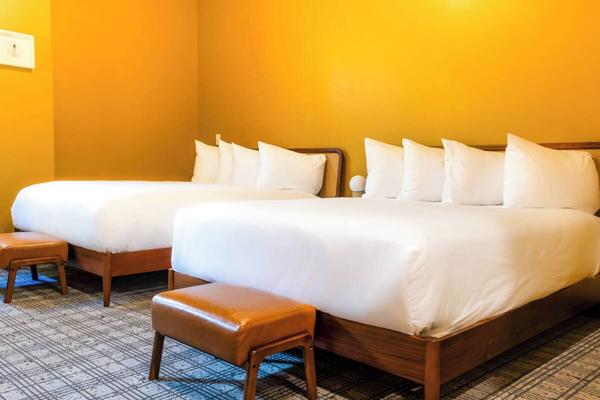 A hotel room with two single beds, a wooden bench, and a patterned carpet.