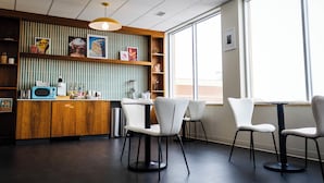 En modern inredning med ett köksområde, vita stolar och ett stort fönster.