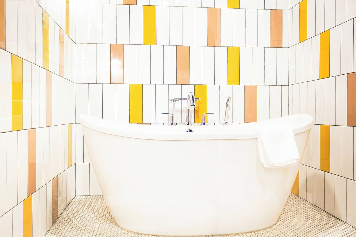 A bathroom with a freestanding bathtub, tiled walls, and a patterned floor.