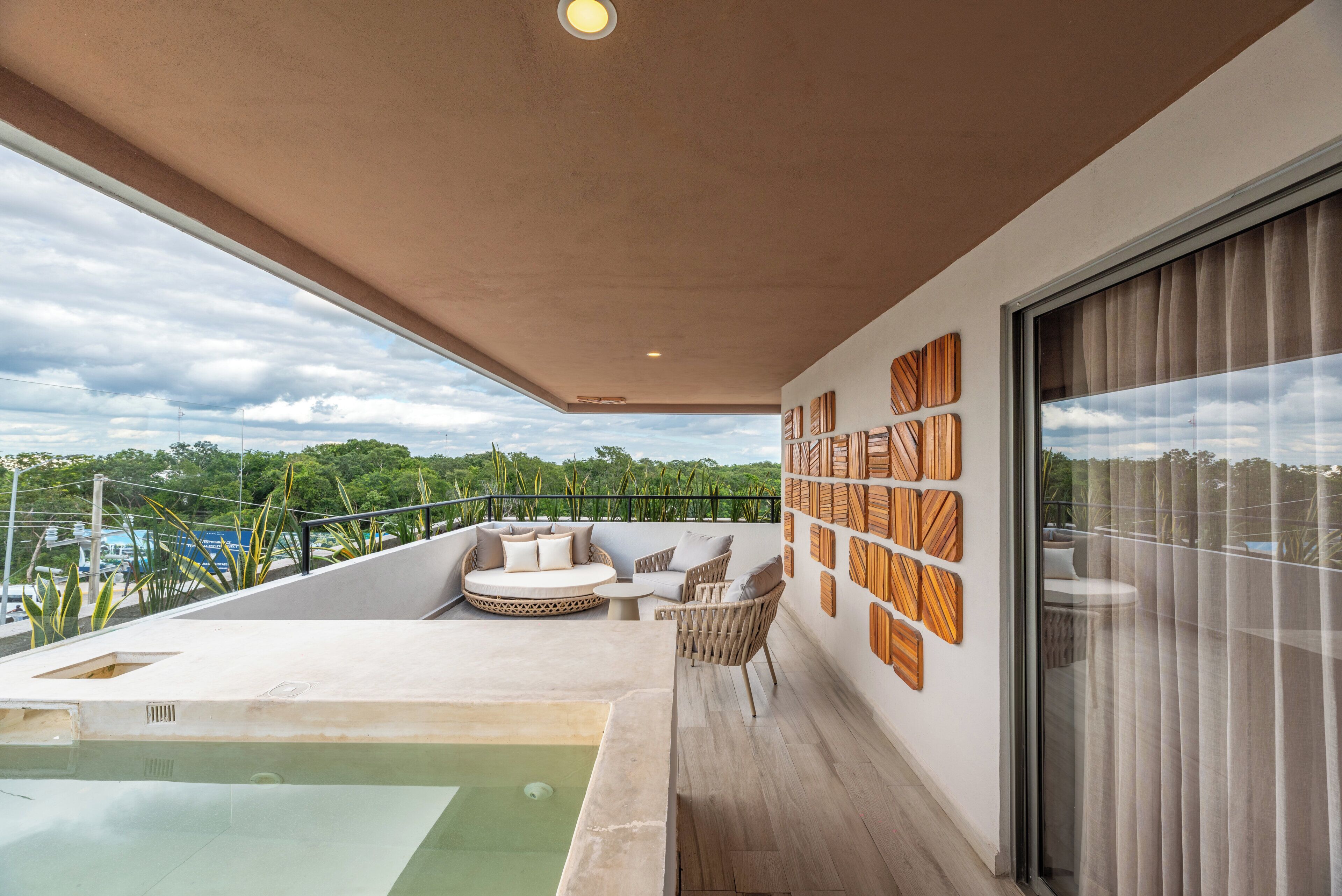 A modern balcony with a pool, seating area, and a cityscape view.