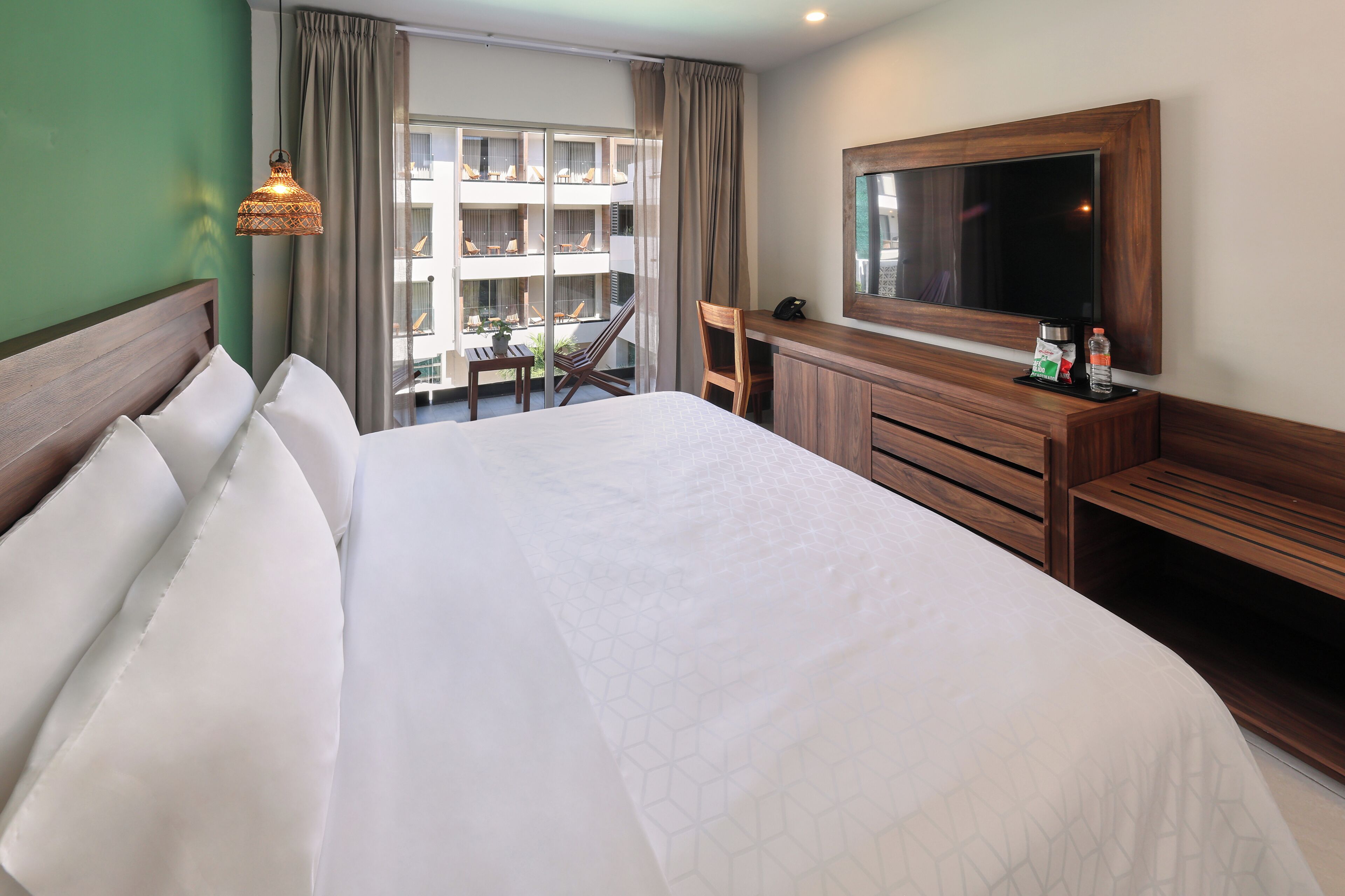 Habitación de hotel con una cama grande, un escritorio, una silla, un televisor y una ventana con cortinas.