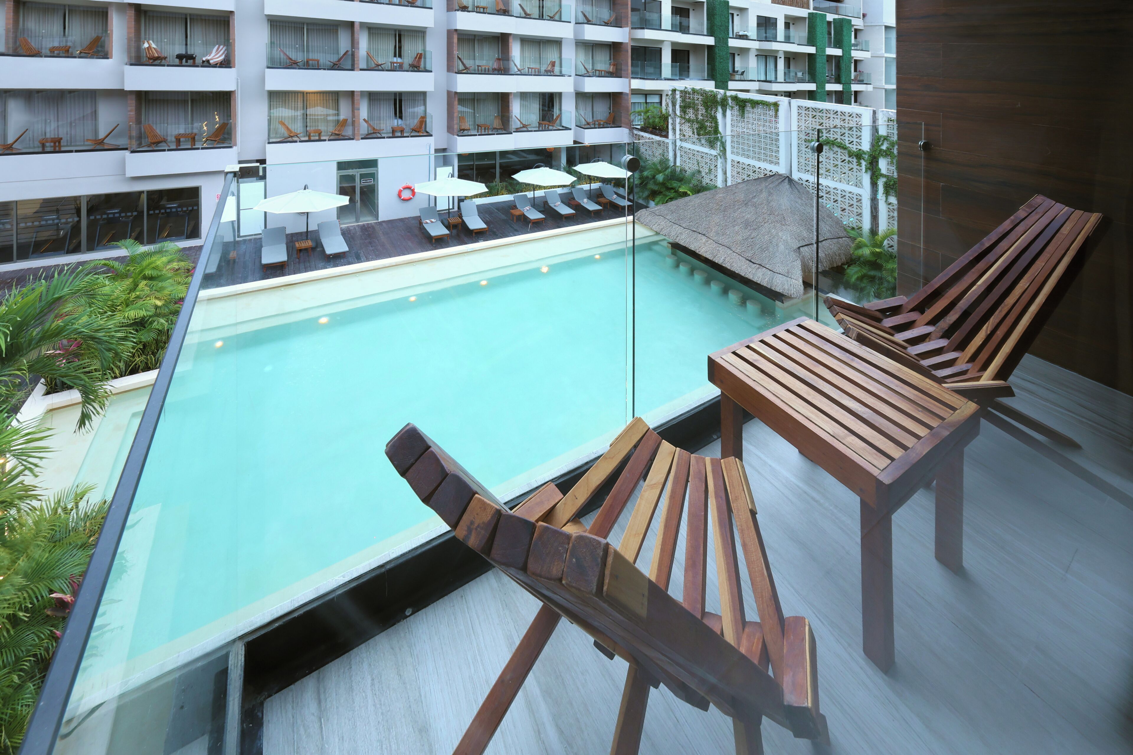 Zona de piscina al terrat amb gandules, ombrelles i vista de l'edifici de l'hotel.