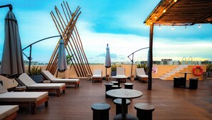 A rooftop lounge with sun loungers, tables, and umbrellas. - Holiday Inn Tulum by IHG (Tulum)