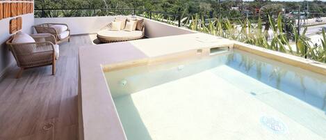A rooftop pool area with seating and a view of the city.
