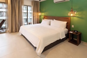 Ein Hotelzimmer mit einem großen Bett, einem Holzkopfende, einem Nachttisch mit Lampe und Blick auf den Außenbalkon.