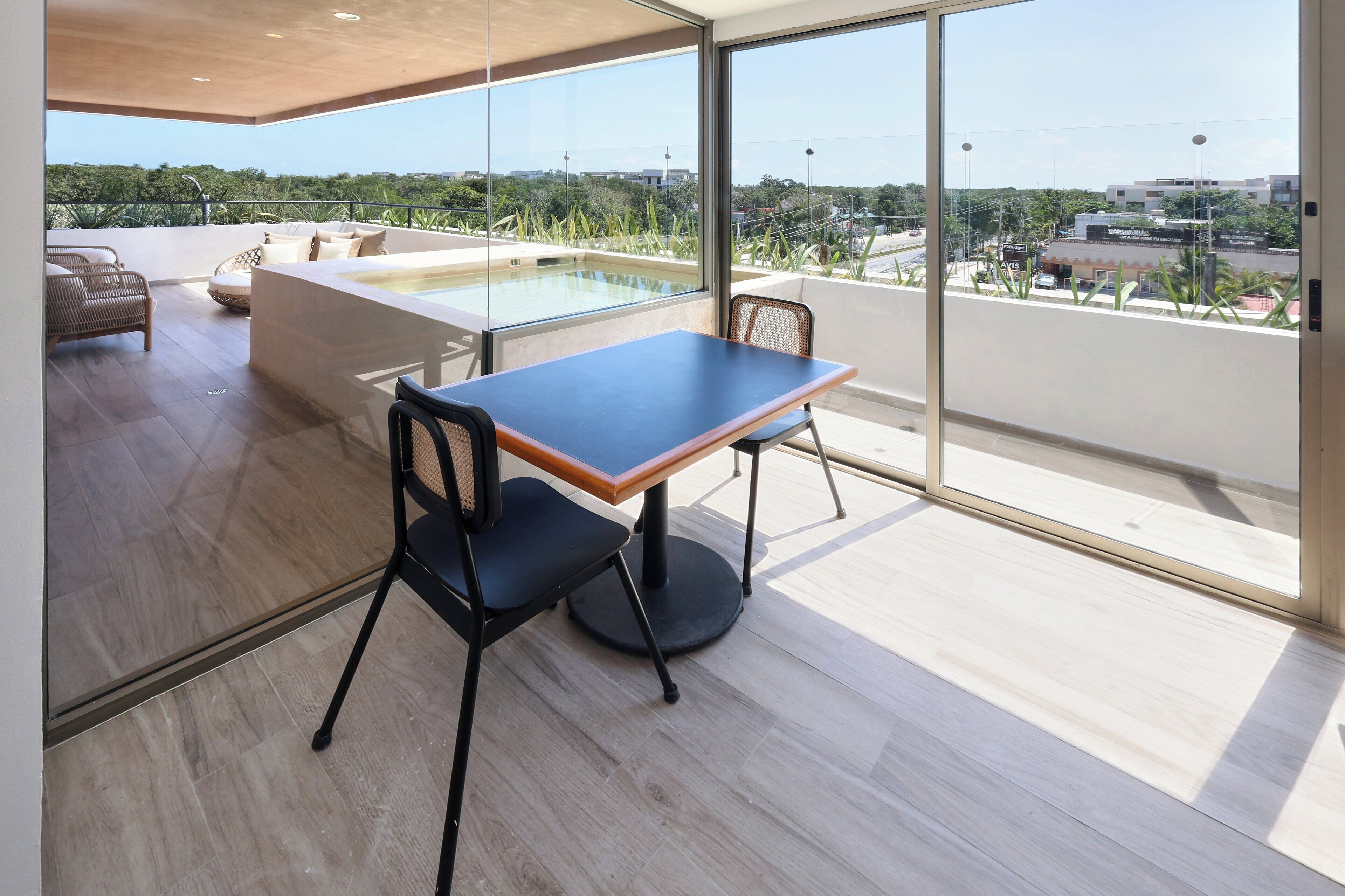 A modern room with a large window, a wooden table, a black chair, and a small pool.