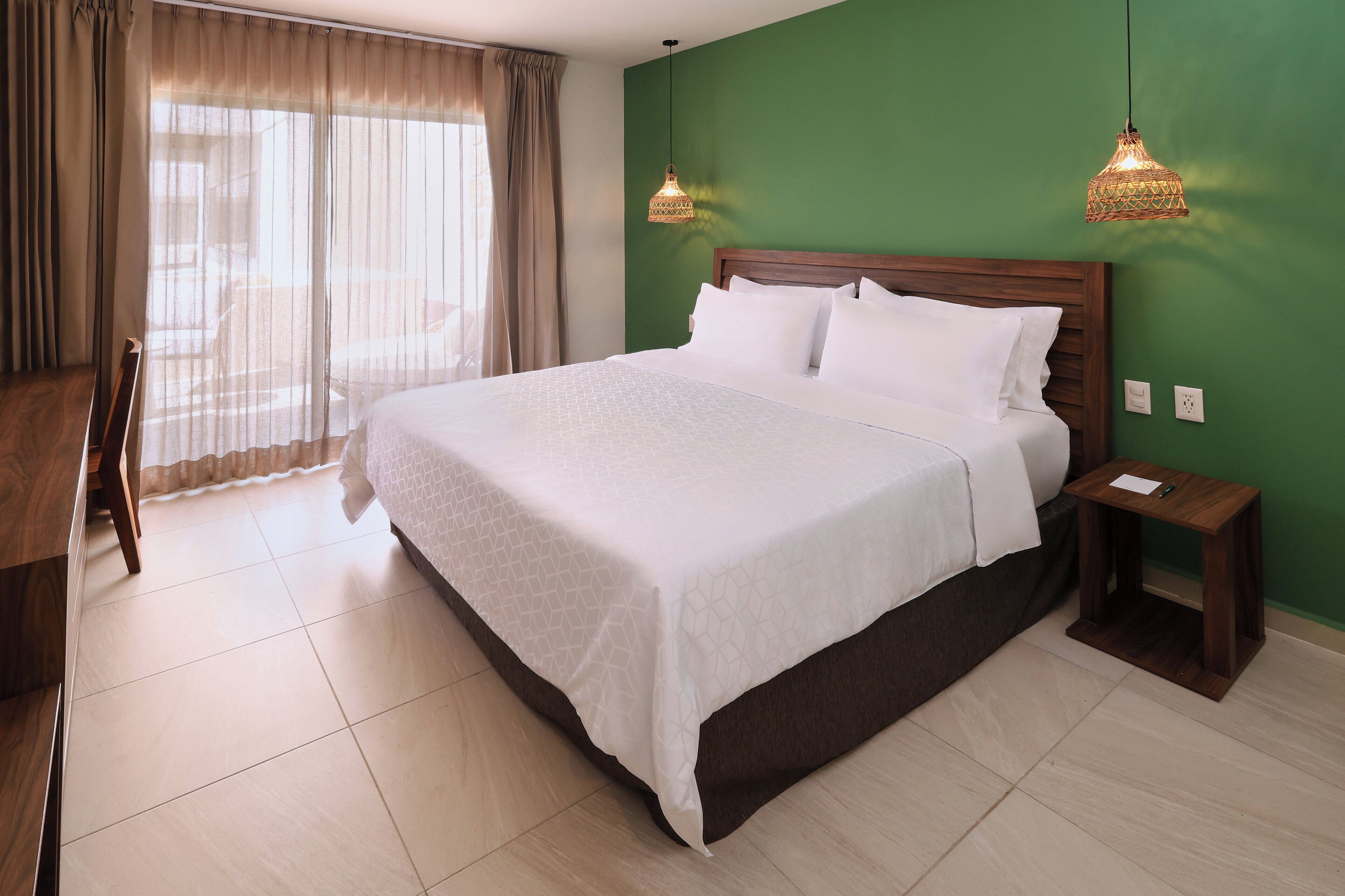 Una cama bien hecha con sábanas blancas, cabecera de madera y dos mesitas de noche con lámparas.
