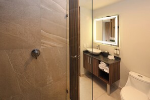Un baño moderno con mampara de vidrio, lavabo con espejo y retrete.