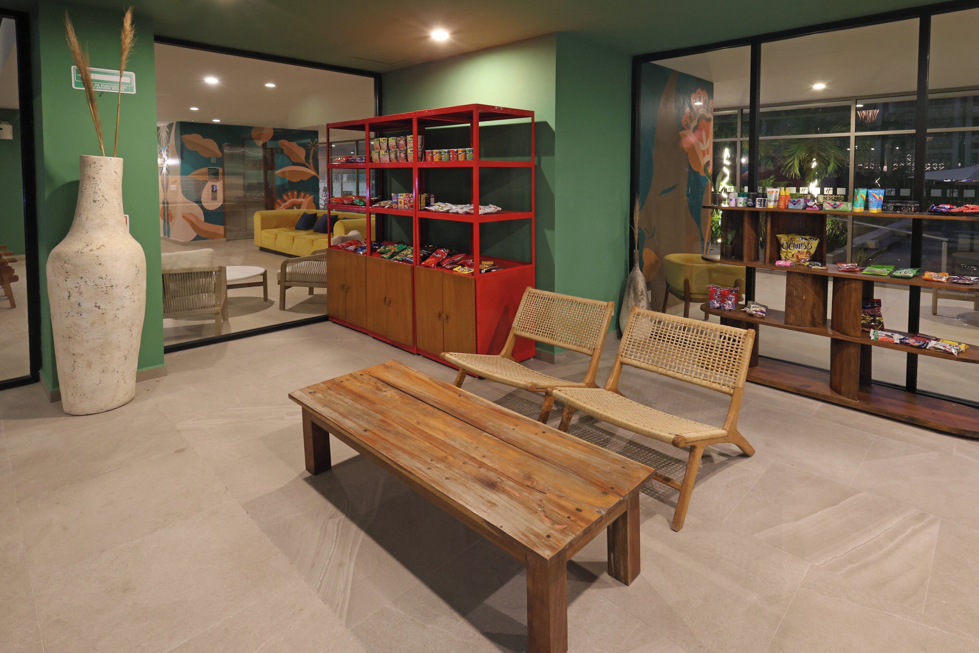 A room with a wooden bench, a red bookshelf, and a large vase.