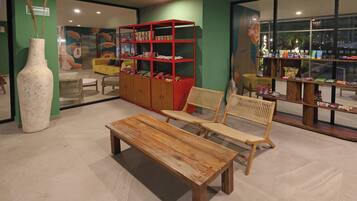 A room with a wooden bench, a red bookshelf, and a large vase.
