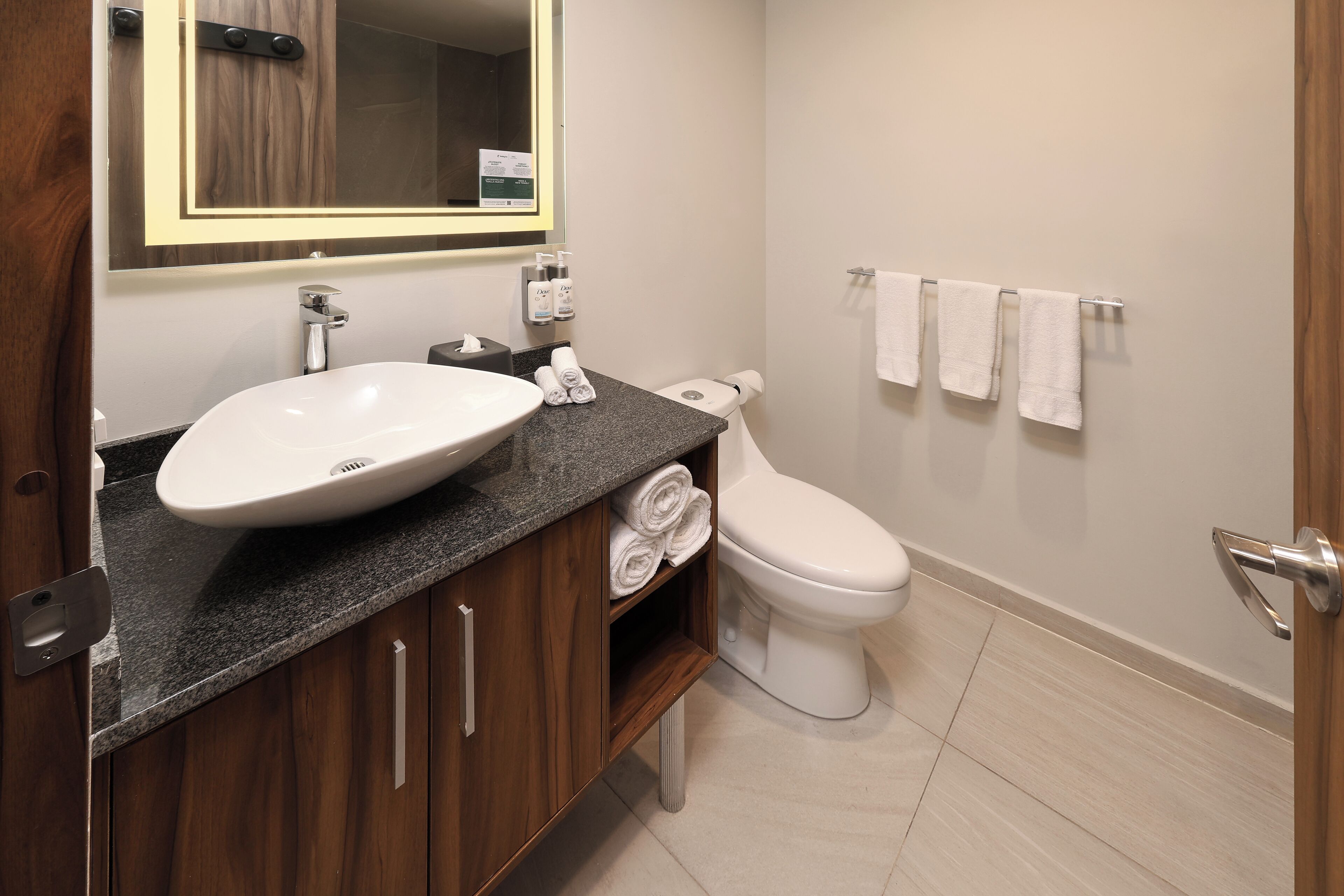 Un baño moderno con un lavamanos grande, inodoro y un perchero para toallas.