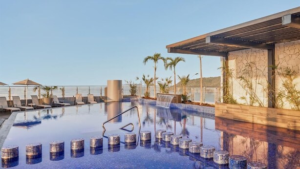 A modern infinity pool with a clear view of the ocean, lounge chairs, and a waterfall feature. - Fiesta Inn Mazatlán (Mazatlán)