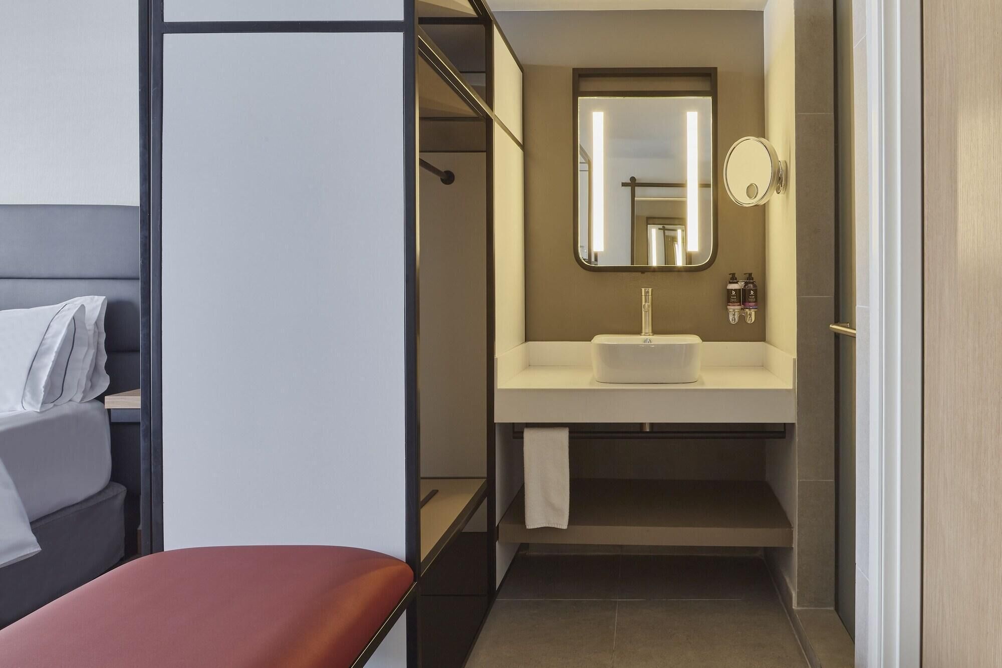 A modern bathroom with a sink, mirror, and towel rack.