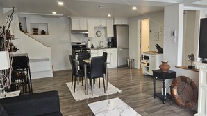 A modern kitchen with white cabinets, a black stove, and a dining area with black chairs.