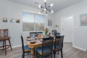 A dining area with a wooden table, black chairs, and a chandelier.