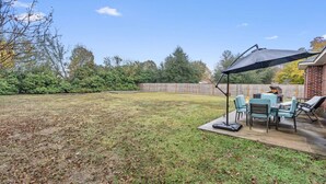 A backyard with a patio area, outdoor furniture, and a grill.