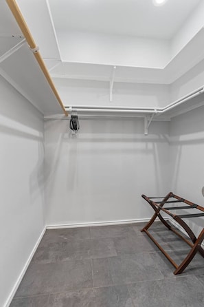 A room with a grey tiled floor, white walls, and a wooden ceiling beam.