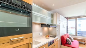 Una cocina compacta con electrodomésticos modernos, armarios de madera y horno empotrado.