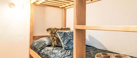 A bunk bed with a wooden frame and a quilted mattress.
