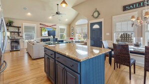 A spacious kitchen with a large island, wooden cabinets, and a dining area with wicker chairs. - 5178 Sea-Cryst * 3 Min Walk to Beach (Kill Devil Hills)