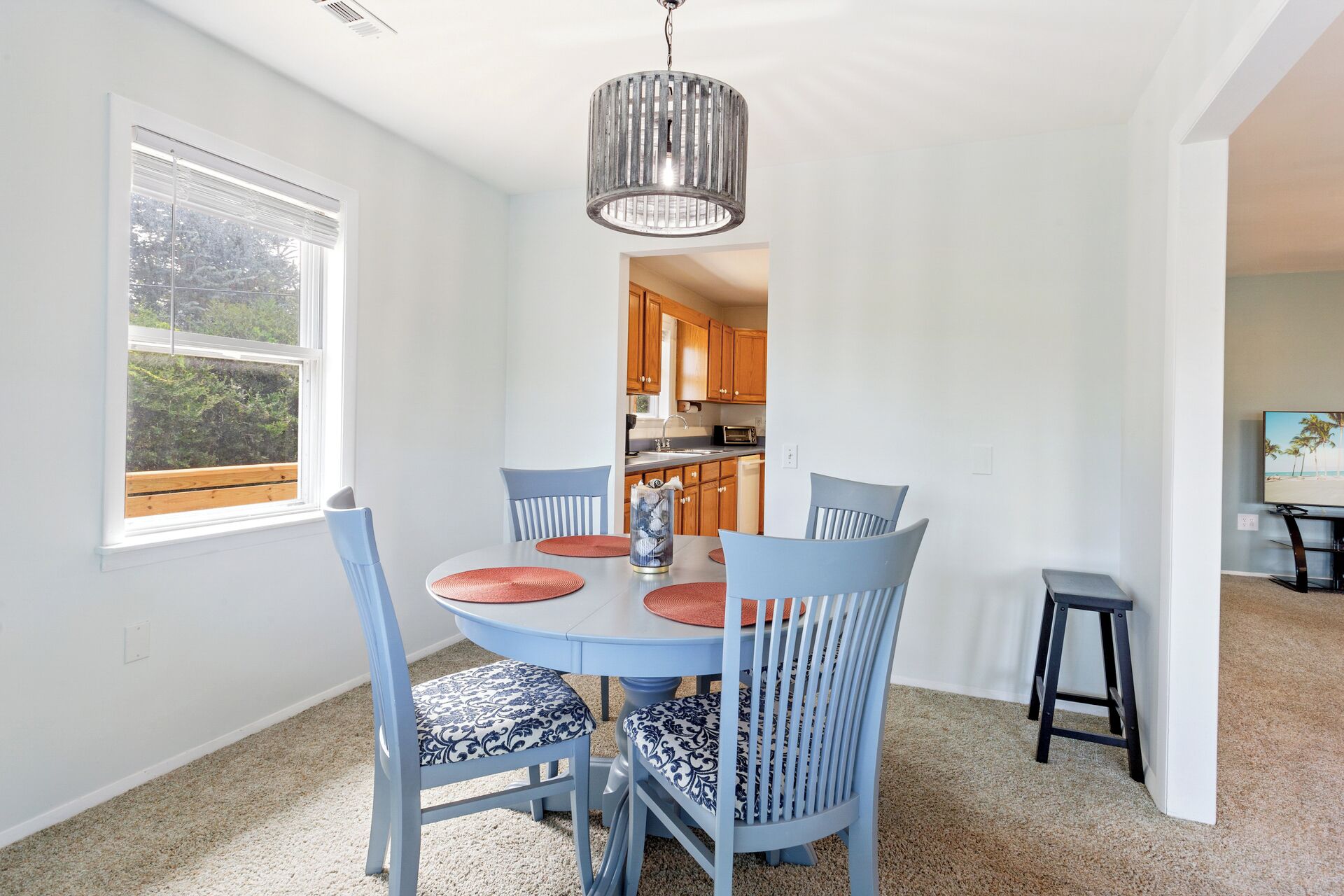 A dining area with a round table, blue chairs, and a hanging light fixture.