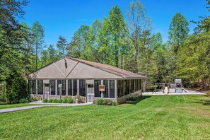 A single-story building with a covered porch, surrounded by a well-maintained lawn and dense trees. - Indoor Pool & Hot Tub Sleeps 4 Mountain Views (Gatlinburg)