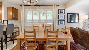 Uma área de refeições com mesa de madeira, cadeiras e um candelabro.