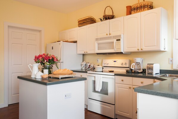 A kitchen with white cabinets, a microwave, a stove, a toaster, and a sink. - Red Plum Town Home| Mountain View & 5 Min. to Town! (Black Mountain)