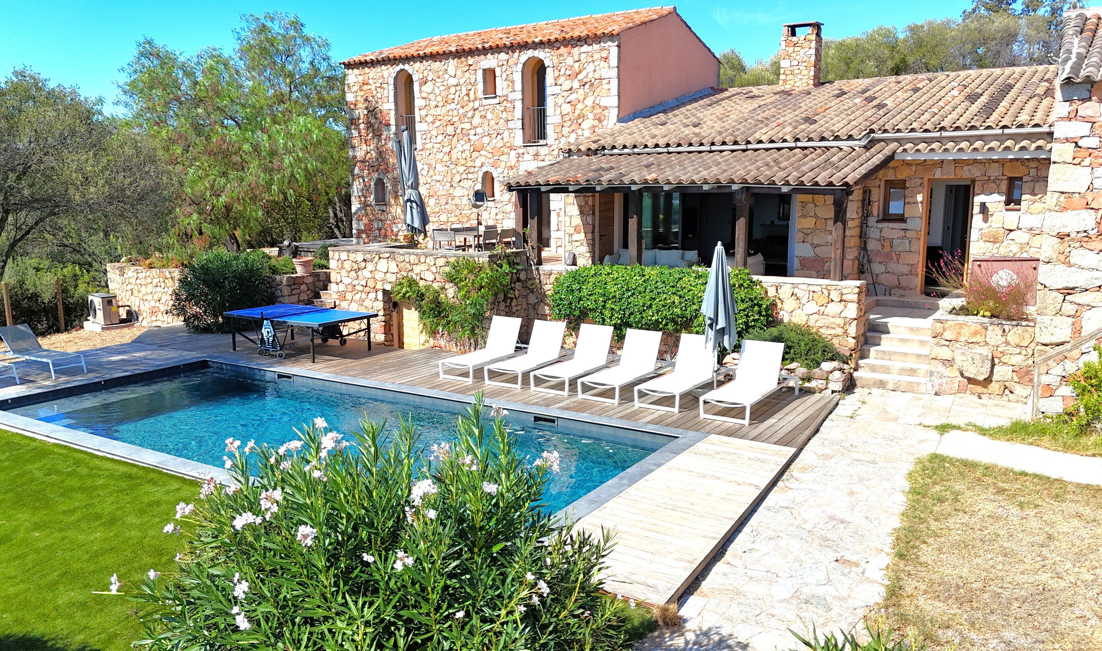 Una villa de piedra con piscina, mobiliario exterior y jardín.