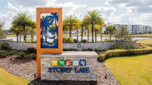 A sign for Storey Lake with palm trees and a body of water in the background.