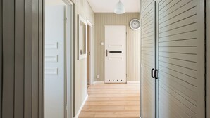 A hallway with wooden floors, white doors, and a clock on the wall.