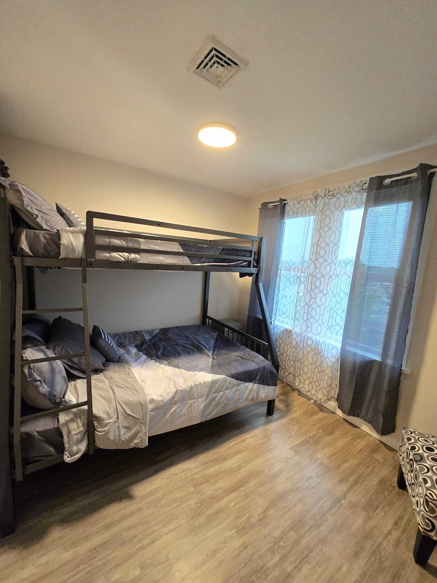 Ein Schlafraum mit Etagenbetten, einem Fenster und Vorhängen.