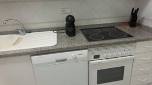 A kitchen with a white sink, a black coffee maker, a stove, and a dishwasher.