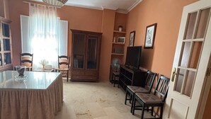 A living room with a dining table, chairs, a TV, and a cabinet.
