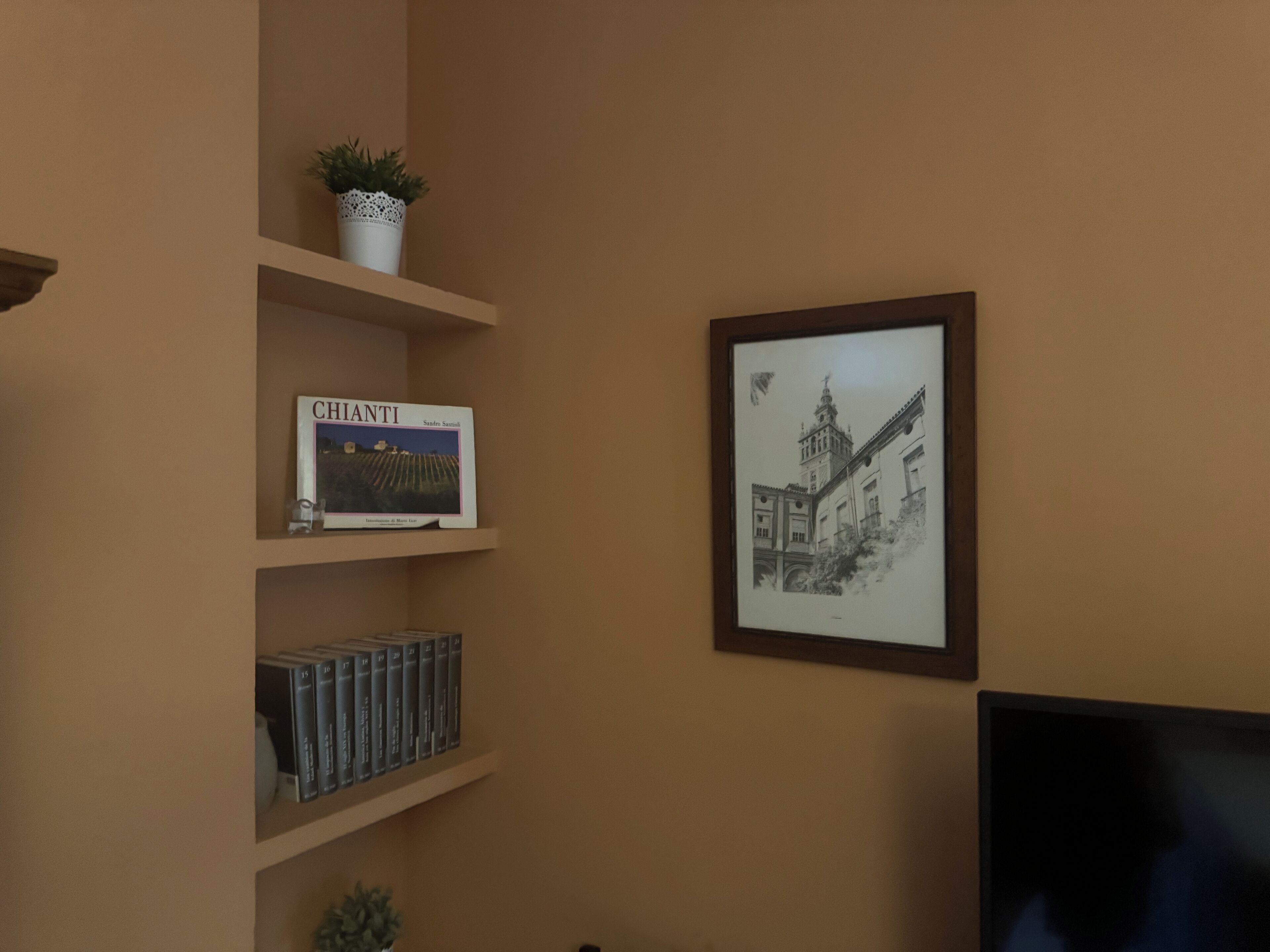 A room with a bookshelf containing books and a framed picture of a building.