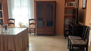 A dining area with a table, chairs, a cabinet, and a television.