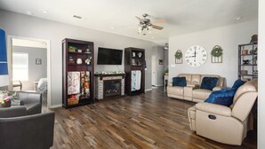 A spacious living room with a fireplace, leather sofas, and a flat-screen TV.