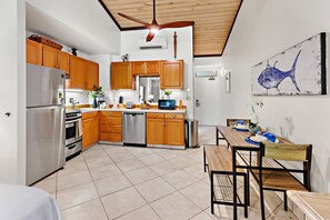 Eine moderne Küche mit Holzschränken, Edelstahlgeräten und einem Essbereich mit Holztisch und Stühlen.