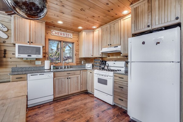 Enjoy cooking in this well-equipped kitchen with a central island, microwave, stove, and refrigerator.