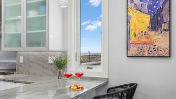 A modern kitchen with a marble countertop, two wine glasses, and a small plant.
