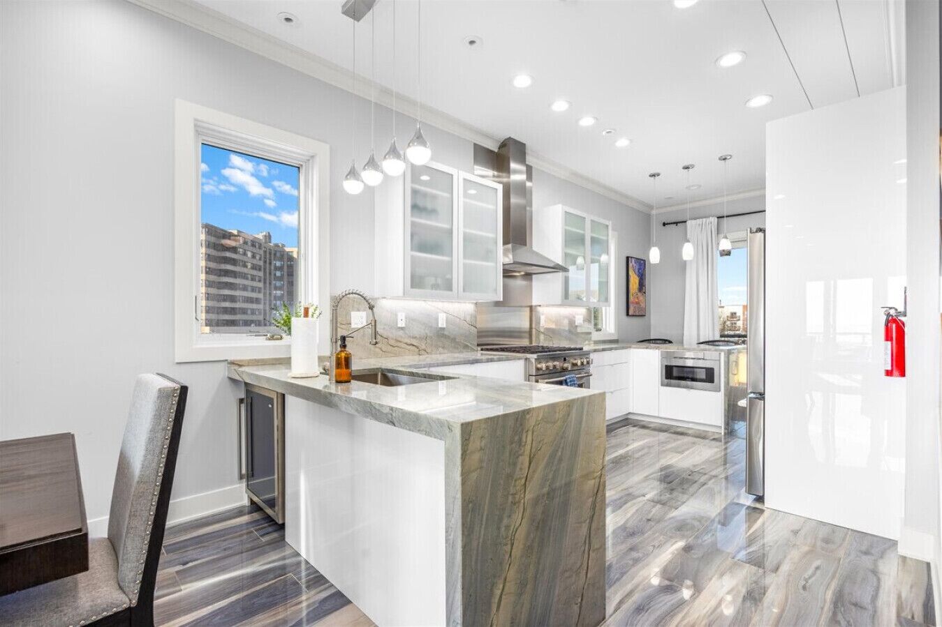 A modern kitchen with a large island, stainless steel appliances, and pendant lighting.