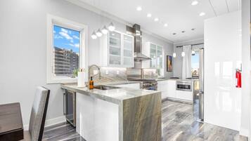 A modern kitchen with a large island, stainless steel appliances, and pendant lighting.