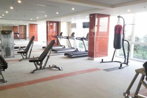 Una palestra con tapis roulant, panche pesi e un sacco da boxe.
