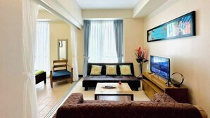 A living room with a sofa, a coffee table, a TV, and a painting on the wall.